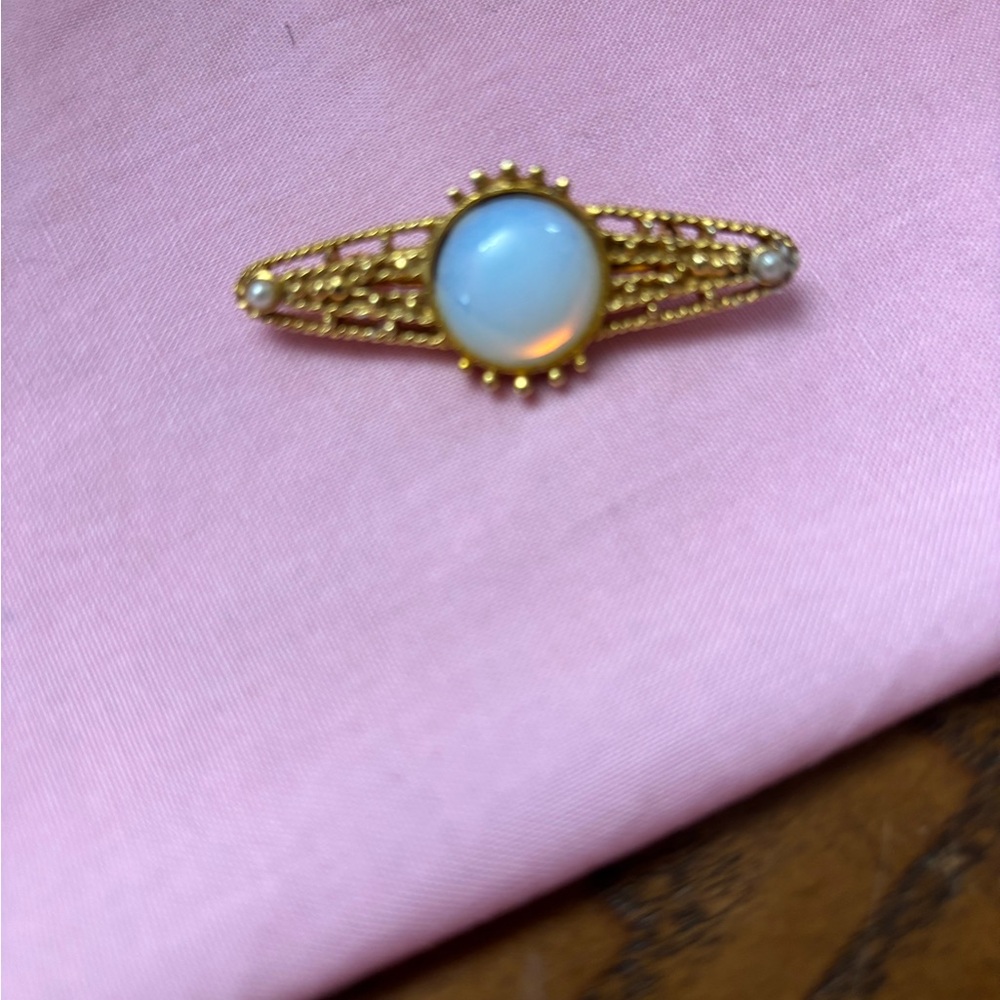 Vin Gold tone moonstone cabochon. bar brooch with filigree scrollwork.